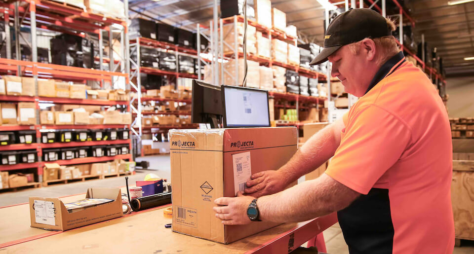 Man in warehouse using Neto ecommerce Pick'n Pack to fulfil orders and label box