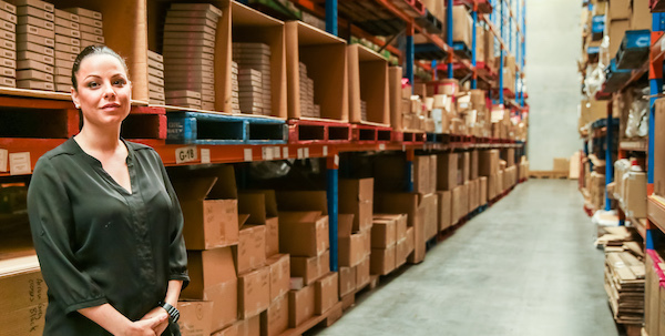 woman standing in tidy warehouse surrounded by boxes